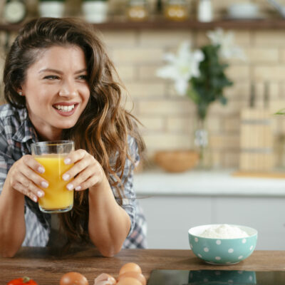 Young woman in kitchen. Beautiful woman in modern kitchen drinking orange juice.