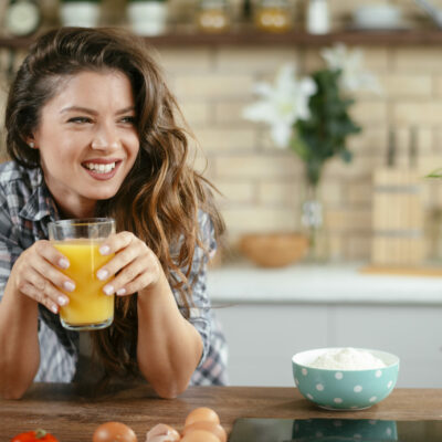 Young woman in kitchen. Beautiful woman in modern kitchen drinking orange juice. Young woman in kitchen. Beautiful woman in modern kitchen drinking orange juice.